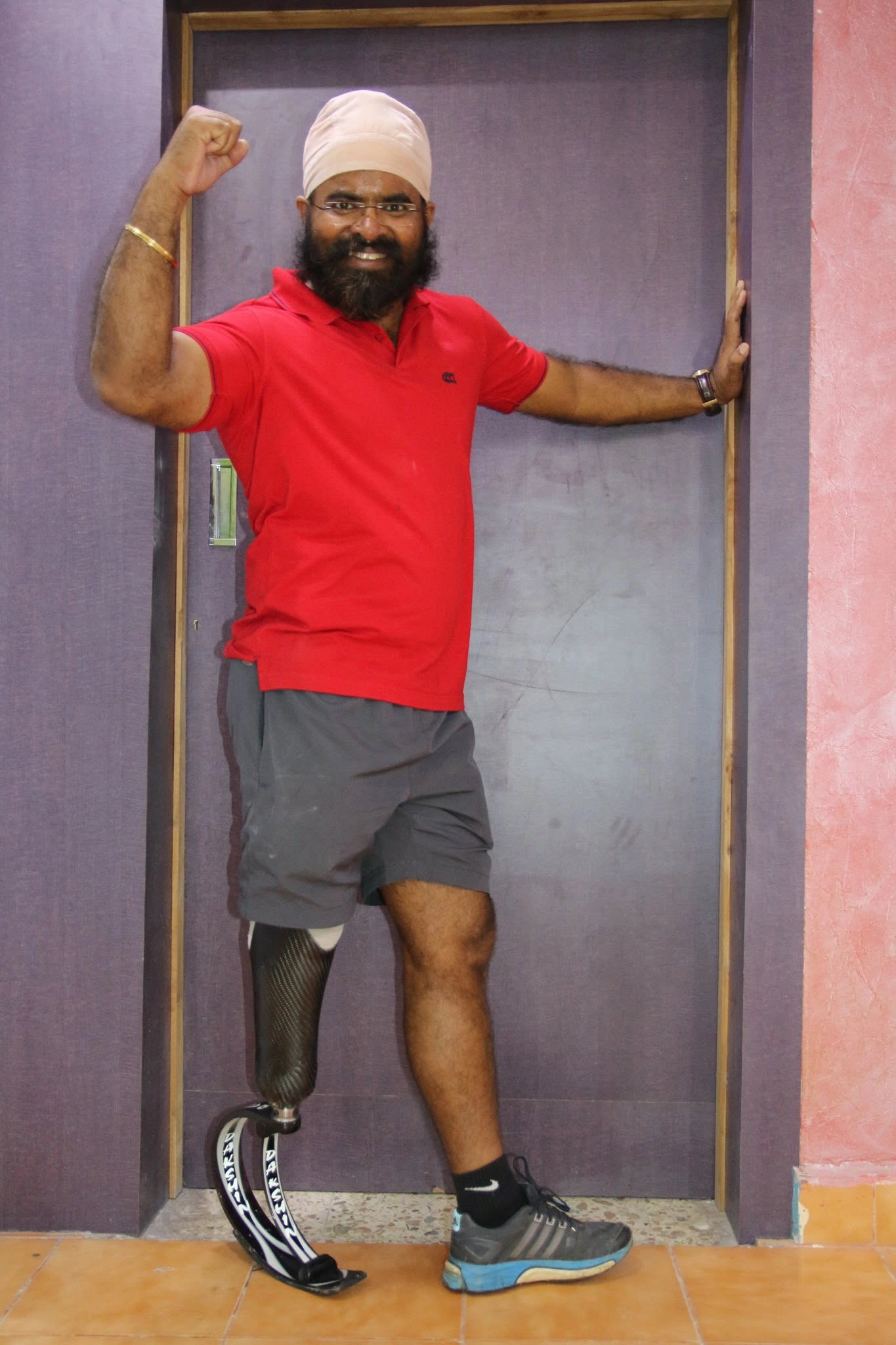 Confident above-knee amputee standing independently with a leg prosthesis at DakshinRehab