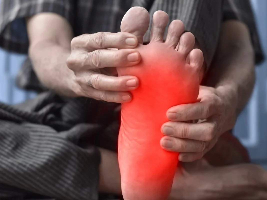 Person holding the sole of the foot, with heel and arch discomfort highlighted