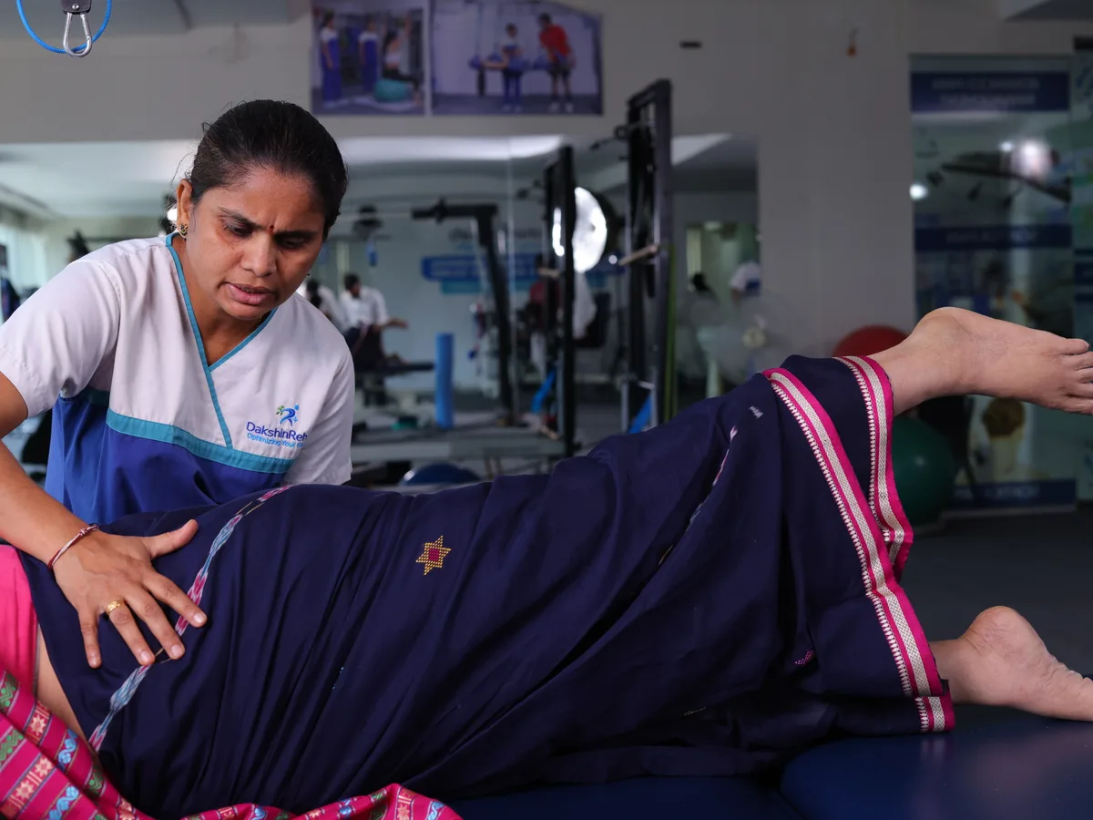 Physiotherapist supervising a side-lying leg exercise with resistance bands above the patient’s knees