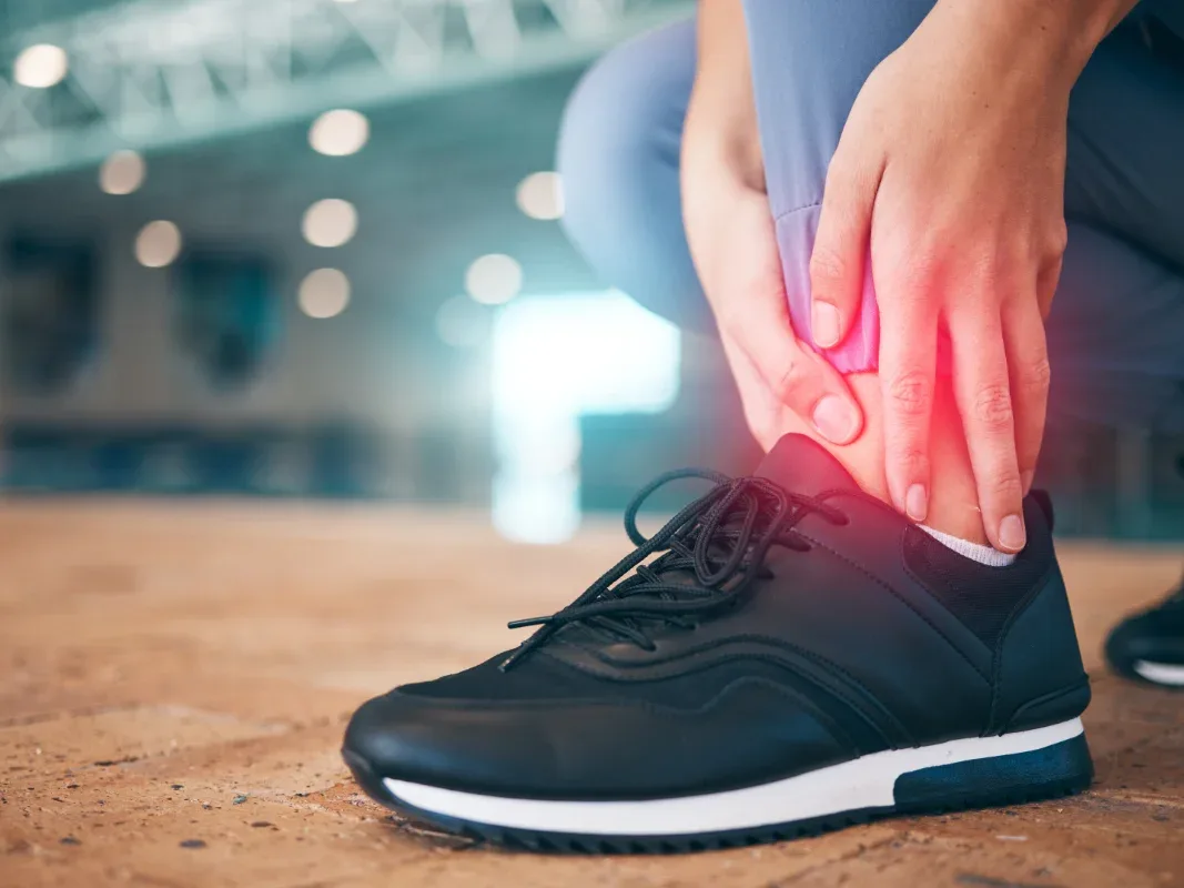 Athlete holding the ankle, with discomfort highlighted