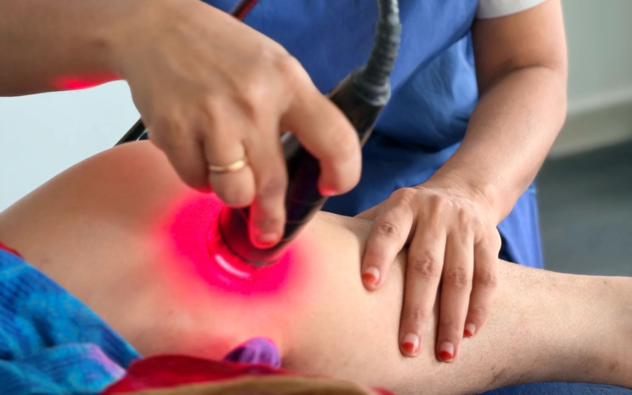 DakshinRehab physiotherapist applying a laser handpiece to a patient’s knee