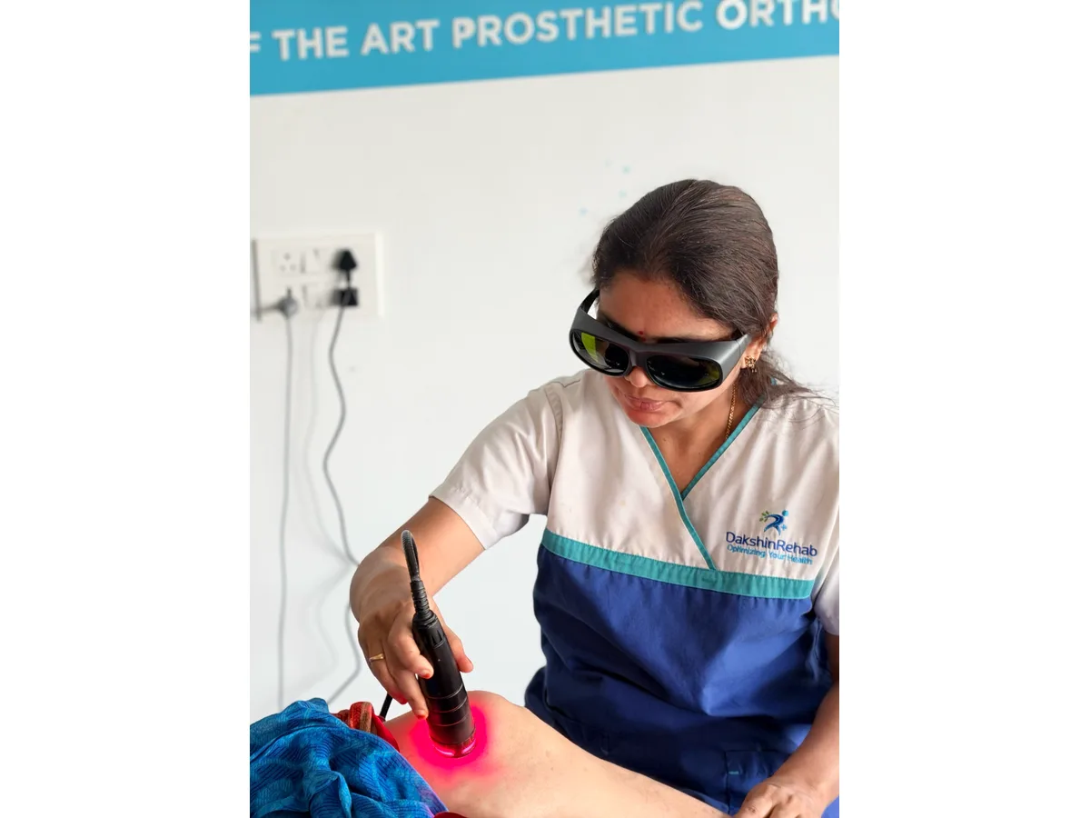 DakshinRehab physiotherapist applying a laser handpiece to a patient’s knee