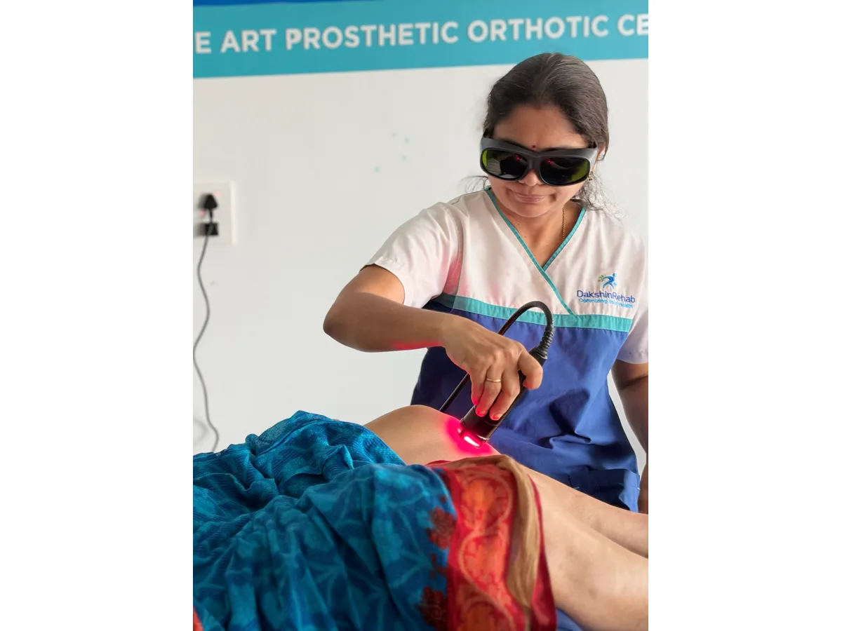 DakshinRehab physiotherapist applying a laser handpiece around a patient’s knee