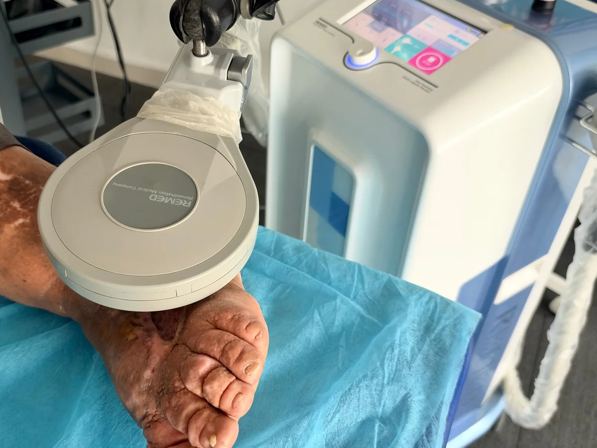 Foot supported on a clinic treatment couch beside the Salus equipment
